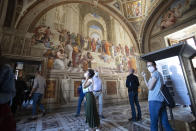 Visitors wearing masks to prevent the spread of coronavirus admire "The School of Athens" fresco by Italian Renaissance artist Raphael inside the Vatican Museum after it reopened, in Rome, Monday, June 1, 2020. The Vatican Museums reopened Monday to visitors after three months of shutdown following COVID-19 containment measures. (AP Photo/Alessandra Tarantino)