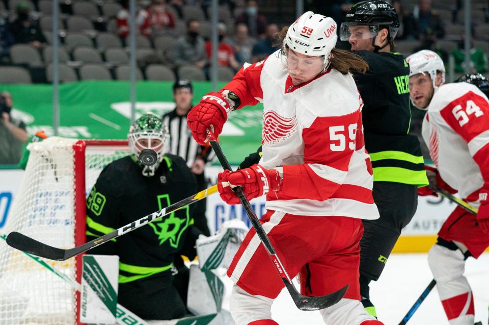 Detroit Red Wings left wing Tyler Bertuzzi (59) tries to control the puck as Dallas Stars defenseman Miro Heiskanen, right, and goaltender Jake Oettinger (29) watch during the first period of an NHL hockey game Thursday, Jan. 28, 2021, in Dallas.