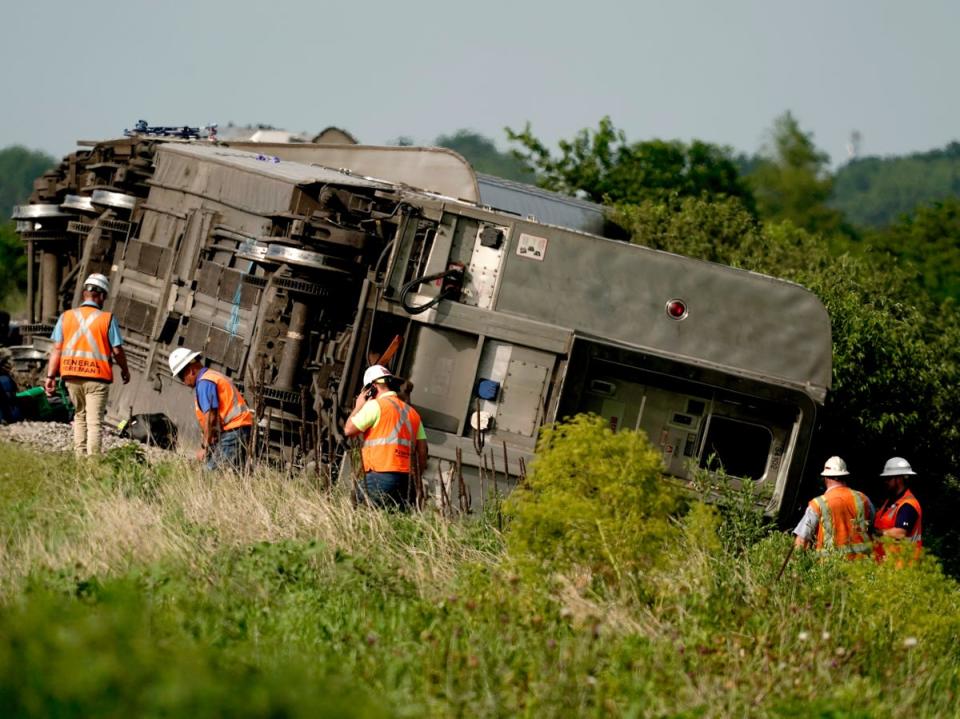 Workers inspect the wreckage of the derailed Amtrak train near Mendon, Missouri (AP)