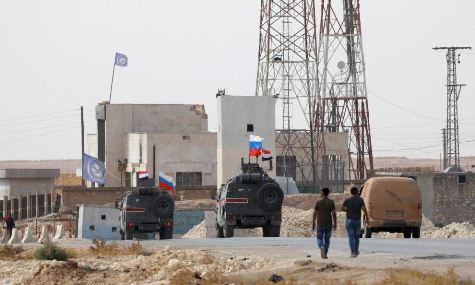 Russian and Syrian flags flutter on military vehicles near Manbij in northern Syria.