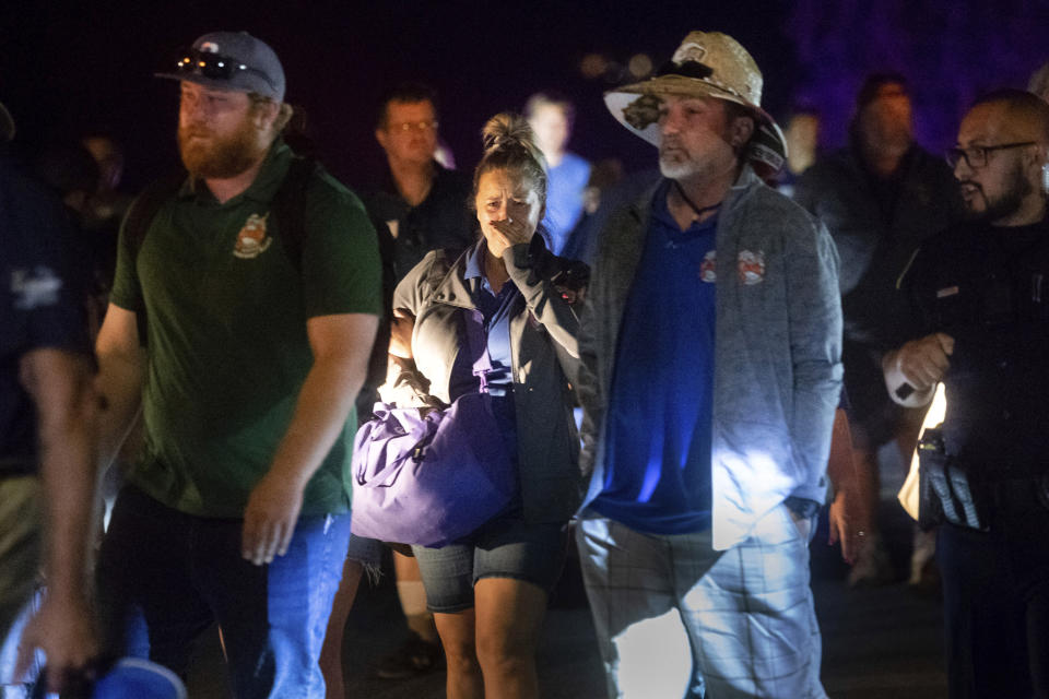 FILE - In this July 28, 2018 file photo, police officers escort people from Christmas Hill Park following a deadly shooting during the Gilroy Garlic Festival, in Gilroy, Calif. A lawsuit announced Tuesday, Nov. 12, 2019, against the Gilroy Garlic Festival Association alleges that negligent security measures allowed a gunman to sneak in and fatally shoot three people. (AP Photo/Noah Berger, File)