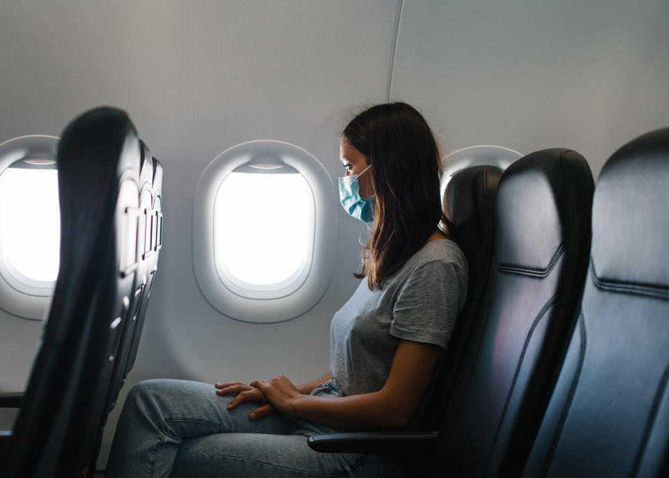 A woman sitting in the window seat of a plane.