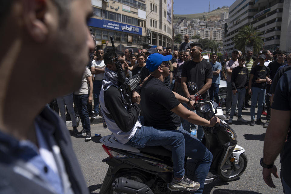 Two Palestinian militants from the Lions' Den group ride a motorbike during the funeral procession of three comrades who were killed by Israeli forces, Hassan Qatnani, Moaz al-Masri and Ibrahim Jabr, in the West Bank city of Nablus, Thursday, May 4, 2023. The killing of Zuhair al-Ghaleeth last month, the first slaying of a suspected Israeli intelligence collaborator in the West Bank in nearly two decades, has laid bare the weakness of the Palestinian Authority and the strains that a recent surge in violence with Israel is beginning to exert within Palestinian communities. (AP Photo/Nasser Nasser)