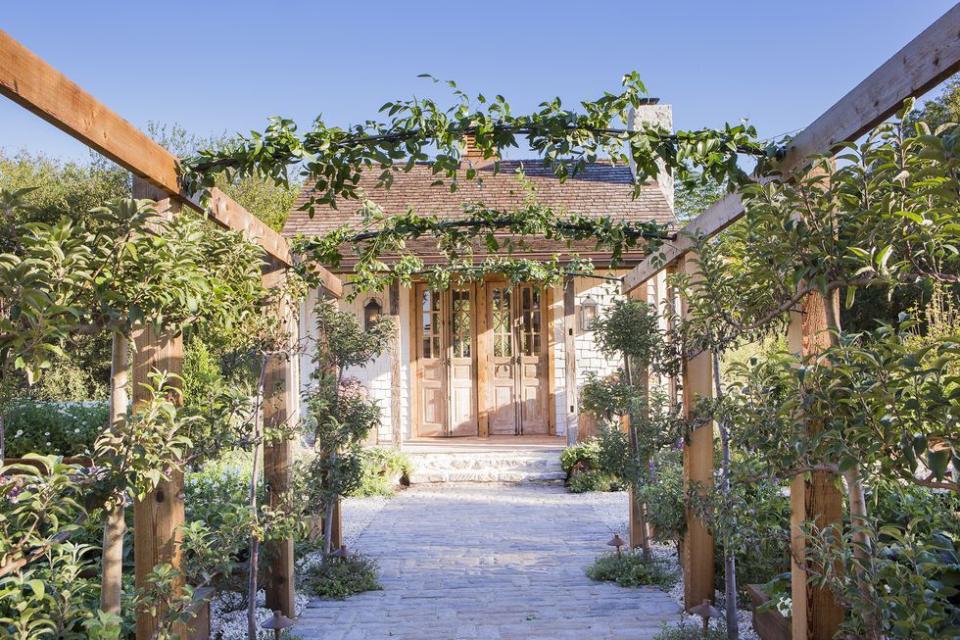 <p>Leave it to Joanna Gaines of <em>Fixer Upper</em> fame to design such a stunning walkway for her garden. The vine-covered arbor overhead gives the outdoor space an ethereal feel.</p><p><strong><a href="https://www.countryliving.com/life/entertainment/g17850558/joanna-gaines-farmhouse-garden/" rel="nofollow noopener" target="_blank" data-ylk="slk:Read more about Joanna Gaines' farmhouse garden.;elm:context_link;itc:0;sec:content-canvas" class="link ">Read more about Joanna Gaines' farmhouse garden.</a></strong></p><p><a class="link " href="https://go.redirectingat.com?id=74968X1596630&url=https%3A%2F%2Fwww.wayfair.com%2FOutsunny--Garden-Arch-Trellis-55.1-W-x-23.6-D-Wood-Arbor-845125-L7184-K%7EOTSU1351.html&sref=https%3A%2F%2Fwww.countryliving.com%2Fgardening%2Fgarden-tours%2Fg1432%2Flandscaping-ideas%2F" rel="nofollow noopener" target="_blank" data-ylk="slk:SHOP ARBOR TRELLISES;elm:context_link;itc:0;sec:content-canvas">SHOP ARBOR TRELLISES</a></p>