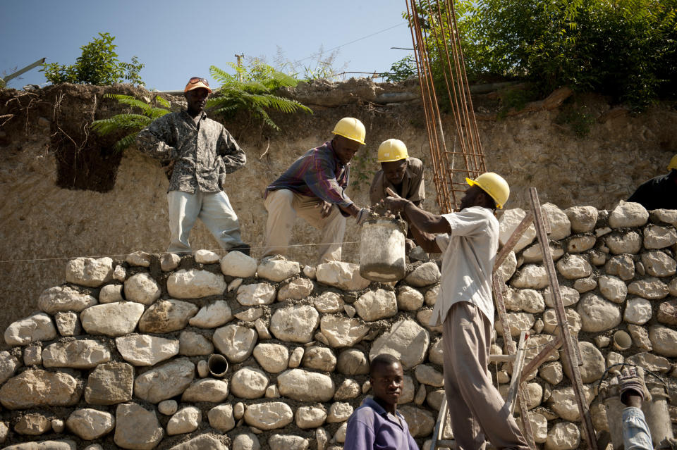 Construction workers pour cement while rebuilding a wall in Port-Au-Prince on April 12, 2011.