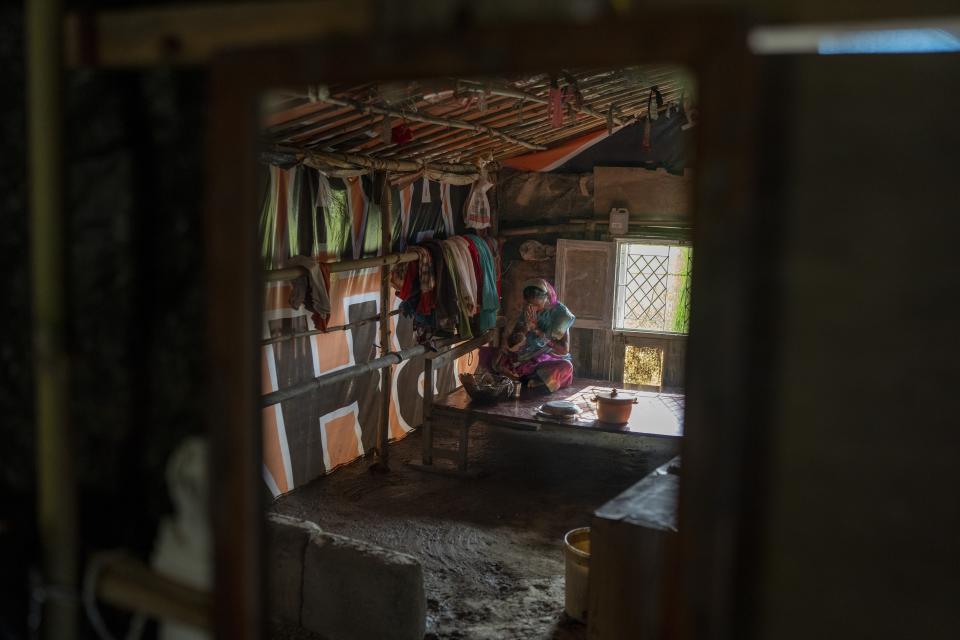 A woman prays inside their makeshift home on the flood plain of Yamuna River, in New Delhi, India, Friday, Sept. 29, 2023. Her family was among those that were displaced by the recent floods in the Indian capital's Yamuna river. (AP Photo/Altaf Qadri)