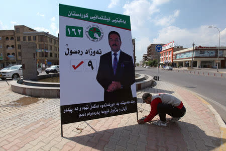 A man works on a campaign poster of candidates ahead of the parliamentary election, in Erbil, Iraq April 15, 2018. REUTERS/Azad Lashkari