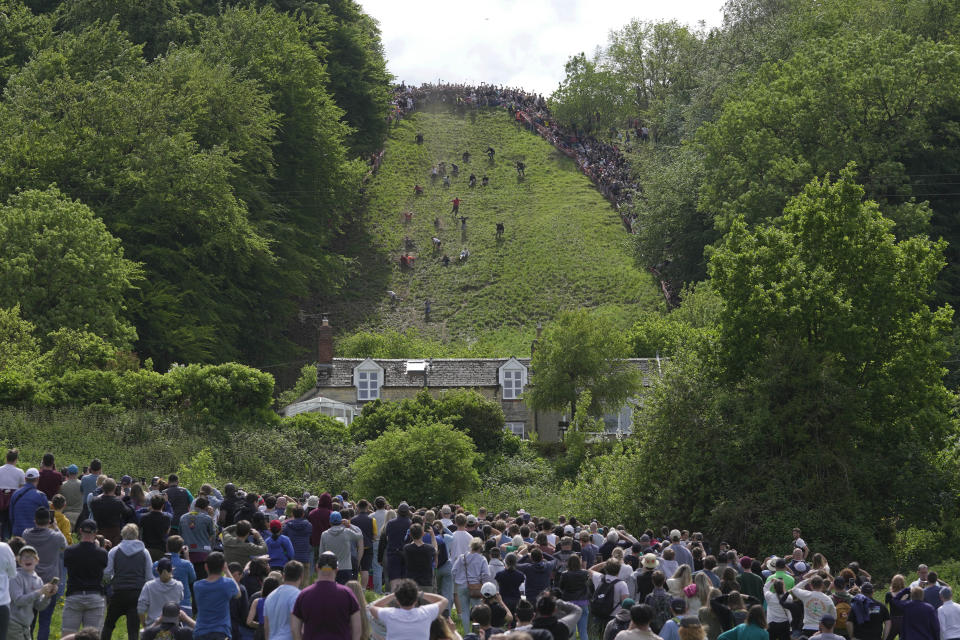 Participants compete in the downhill race during the Cheese Rolling contest at Cooper's Hill in Brockworth, Gloucestershire, Monday May 29, 2023. The Cooper's Hill Cheese-Rolling and Wake is an annual event where participants race down the 200-yard (180 m) long hill chasing a wheel of double gloucester cheese. (AP Photo/Kin Cheung)