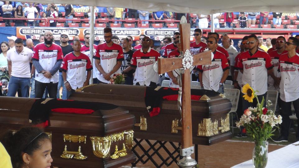 The caskets with the bodies of former major league baseball players Luis Valbuena and Jose Castillo are draped with their uniforms and surrounded by teammates from Cardenales de Lara, during a Mass at a baseball stadium in Barquisimeto, Venezuela, Friday, Dec. 7, 2018. The two were killed in a car crash caused by highway bandits who then robbed them, officials said Friday. The 33-year-old Valbuena and 37-year-old Castillo died late Thursday when their SUV crashed as it tried to veer around an object placed in the road, Yaracuy state Gov. Julio Leon Heredia said on his Twitter account. (AP Photo/Nestor Vivas)