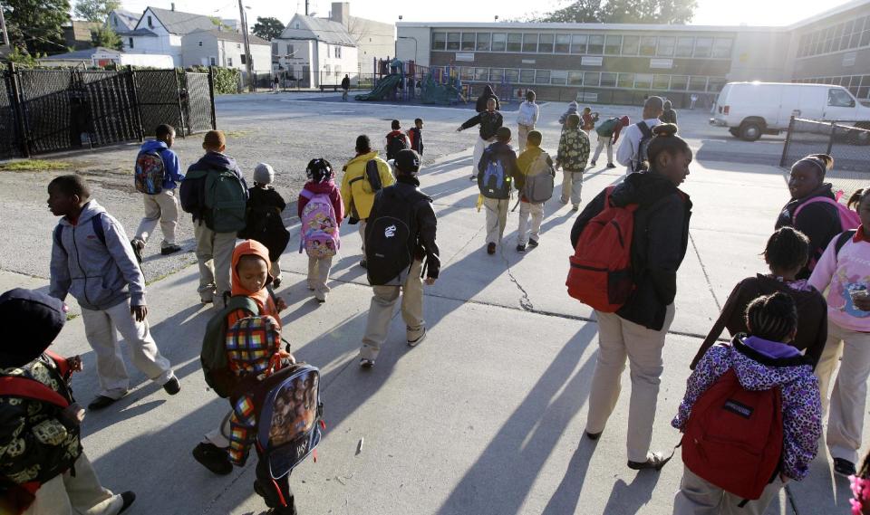 Students walk through the gates outside Benjamin E. Mays Academy, Wednesday morning, Sept. 19, 2012, after Chicago teachers voted to suspend their first strike in 25 years. Union delegates voted overwhelmingly Tuesday night to suspend the walkout after discussing a proposed contract settlement with the nation's third largest school district. (AP Photo/M. Spencer Green)