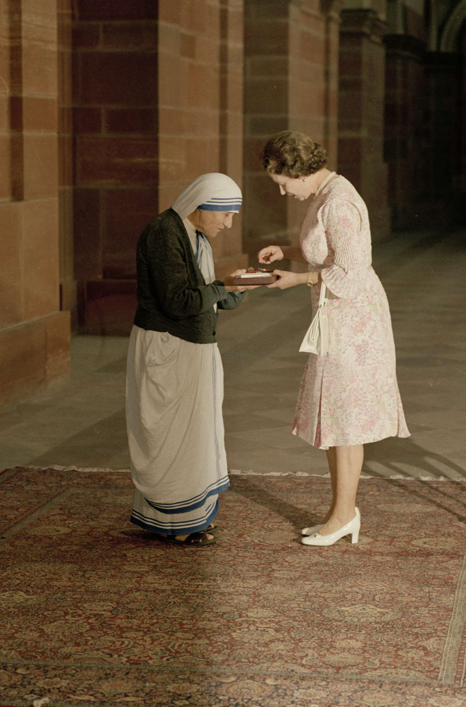 With heads bowed, Queen Elizabeth II and Mother Teresa look at the Insignia of the Honorary Order of Merit which Her majesty has just presented to the Lady of Calcutta, at the Rashtrapati Shavar, in New Delhi, Nov. 24, 1983. (AP Photo)