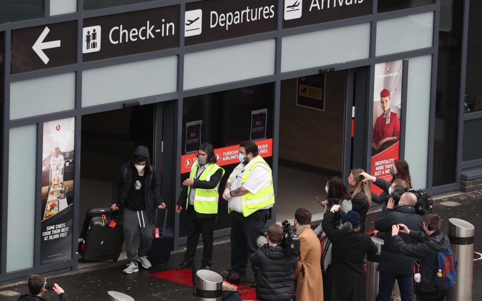 The media film a passenger as he leaves Edinburgh airport after entering the country on the first day that travellers flying directly into Scotland on international flights have to self-isolate for 10 days in a quarantine hotel room - Andrew Milligan/PA