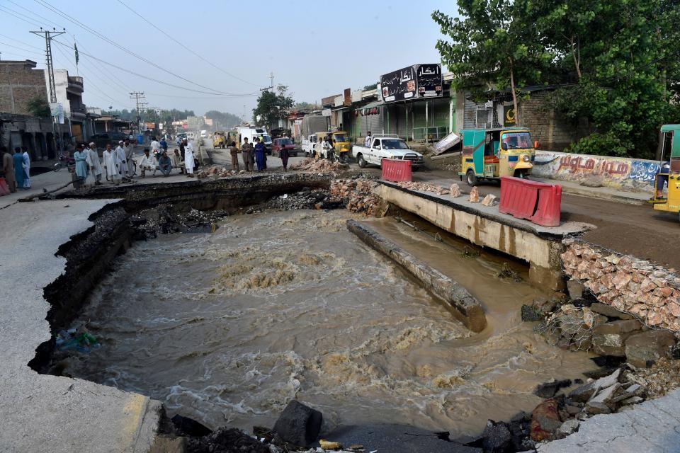 Residents gather beside a road damaged by flood waters following heavy monsoon rains in Charsadda district of Khyber Pakhtunkhwa, Pakistan, August 29, 2022. / Credit: ABDUL MAJEED/AFP/Getty