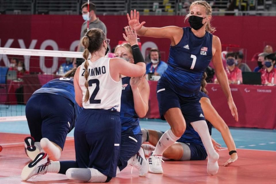 USA's Lora Webster (R) celebrates with Bethany Zummo (2nd R) during the sitting volleyball pool match during the Tokyo 2020 Paralympic Games