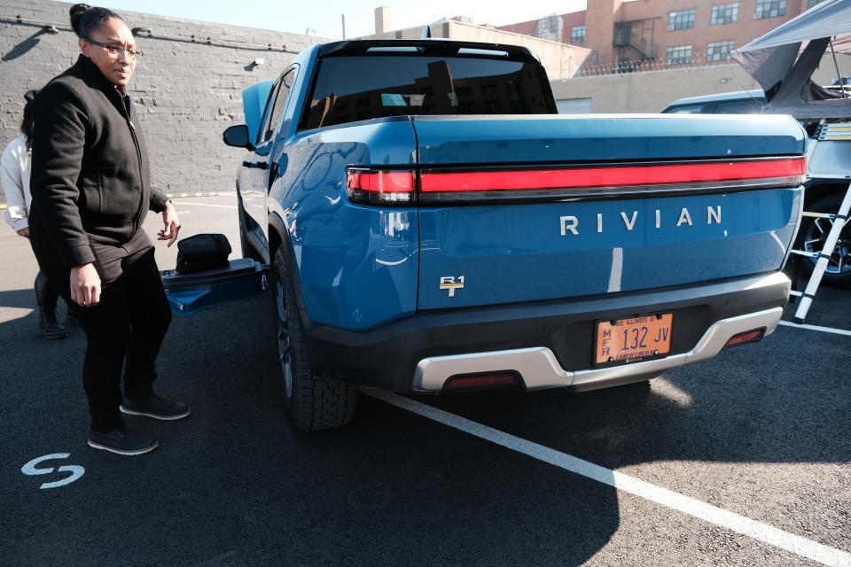 NEW YORK, NEW YORK - NOVEMBER 09: Rivian employees stand beside the new all-electric pickup truck by Rivian, the R1T, as it sits at one of its facilities on November 09, 2021 in the Brooklyn borough of New York City. The company, which makes electric trucks and is backed by Amazon and Ford, has has been valued at $64 billion ahead of its IPO tomorrow.  (Photo by Spencer Platt/Getty Images)