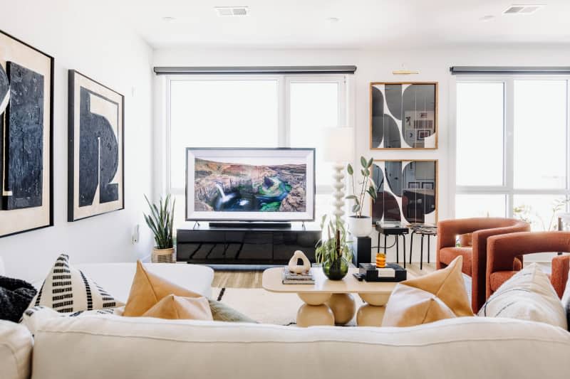 white living room with white sofa, black, neutral and white decor, and lots of curved edge furniture