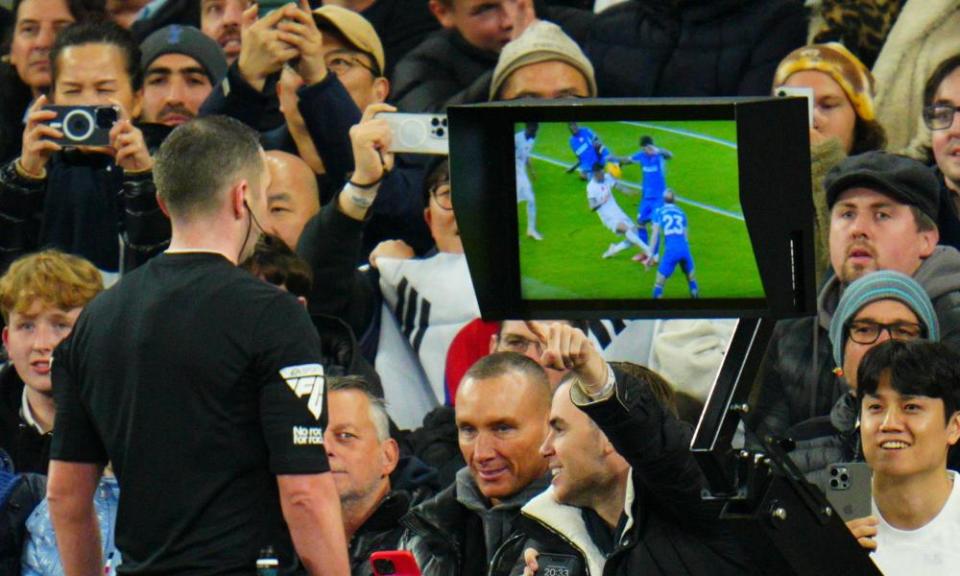 Referee Michael Oliver checks the VAR monitor before awarding Chelsea a penalty and sending off Cristian Romero of Tottenham Hotspur.