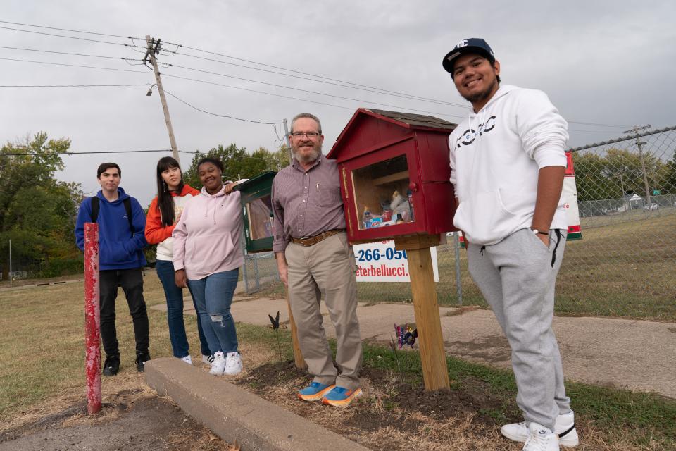 Highland Park senior Henry Guerra, right, stands next to TCALC woodshop teacher Mark Richards and, from left, junior Jay Cohagen, senior Gloria Mendez and senior Taah Smith-Hailey. Richards crafted the green and red lending library and blessing box while the Highland Park students and members of Scots Movement Club take care filling the boxes that are located outside the school.