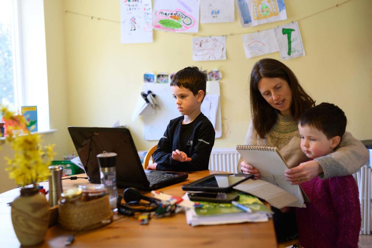 Leo (centre), aged 6, and Espen, aged 3, are assisted by their mother Moira as they homeschool and navigate online learning resources provided by their infant school in the village of Marsden, near Huddersfield: AFP via Getty Images