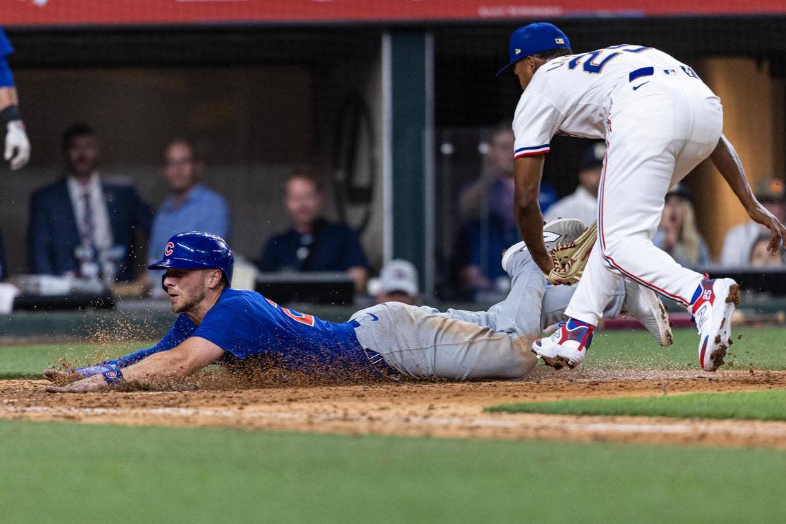 Chicago Cubs first baseman Michael Busch (29) slides home and scores the go ahead run past Texas Rangers relief pitcher Jose Leclerc (25) during the ninth inning in their season opener at Globe Life Field in Arlington on Thursday, March 28, 2024.