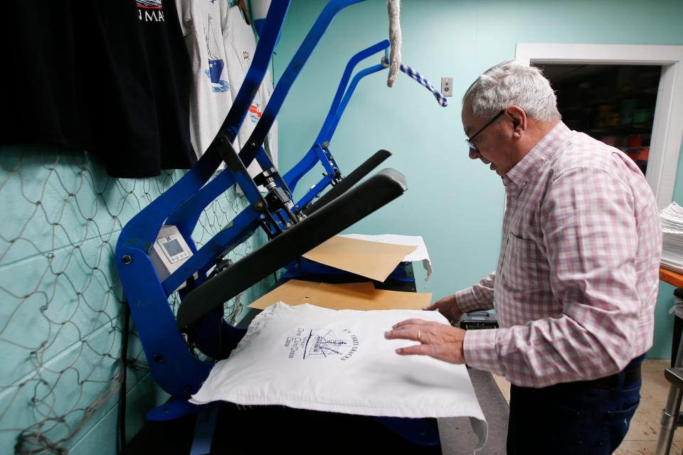 Gil Botelho dries the screen printed scallop bags he is making at the recently opened Ocean Drive Screenprinting on MacArthur Drive in New Bedford.