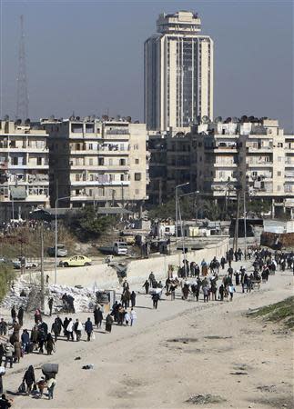 Civilians carry their belongings as they walk at the Karaj al-Hajez crossing, a passageway separating Aleppo's Bustan al-Qasr, which is under the rebels' control and Al-Masharqa neighbourhood, an area controlled by the regime February 9, 2014. REUTERS/Hosam Katan