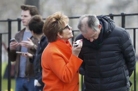 People listen and watch on their mobile devices as Scotland's First Minister Nicola Sturgeon demands a new independence referendum to be held in late 2018 or early 2019, once the terms of Britain's exit from the European Union have become clearer, outside Bute House, in Edinburgh, Scotland, Britain March 13, 2017. REUTERS/Russell Cheyne