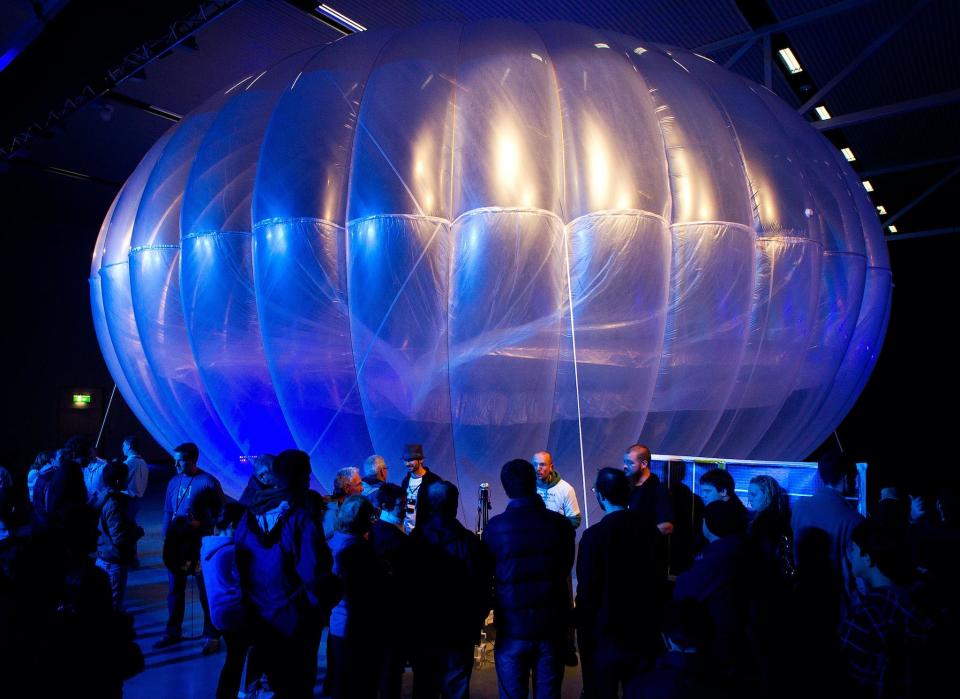 Visitors stand next to a high altitude WiFi internet hub, a Google Project Loon balloon, on display at the Airforce Museum in Christchurch on June 16, 2013: AFP PHOTO / MARTY MELVILLE