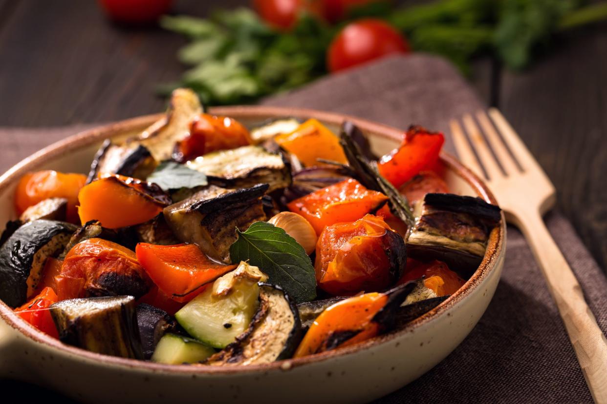 Air fried ratatouille, Italian-style in earthenware bowl with wooden serving fork with blurred background