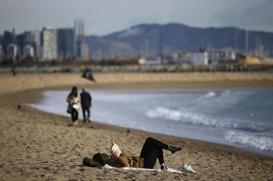 <em>Una mujer lee un libro en la playa de la Barceloneta, en Barcelona. Manu Fernandez (AP)</em>