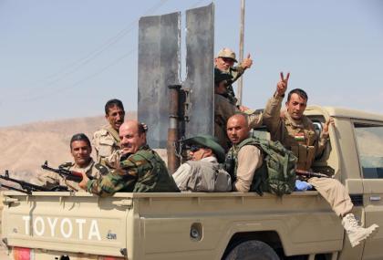 Combatientes kurdos iraquíes (peshmerga) saludan a la cámara en una camioneta que se dirige a la presa de Mosul recuperada a los yihadistas, el domingo 17 de agosto al norte de Irak