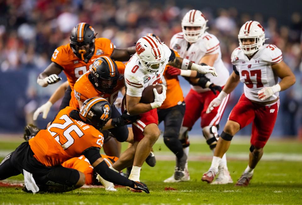 Badgers running back Braelon Allen tries to break free from Oklahoma State defensive players during the first half of the Guaranteed Rate Bowl on Tuesday.