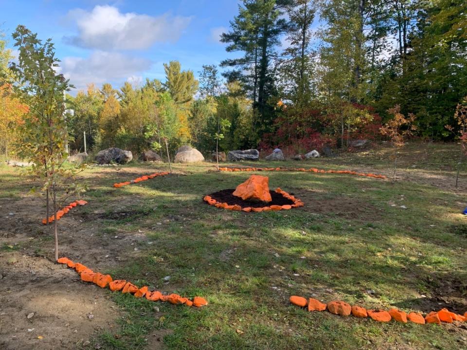 Children's shoes left on Parliament Hill in 2021 after the discovery of the suspected graves of children near former Canadian residential schools sites have now been buried on a hill overlooking a First Nation-operated school in Kitigan Zibi Anishinābeg, an Algonquin First Nation located about 130 kilometres north of Ottawa.  (Guy Quenneville/CBC - image credit)