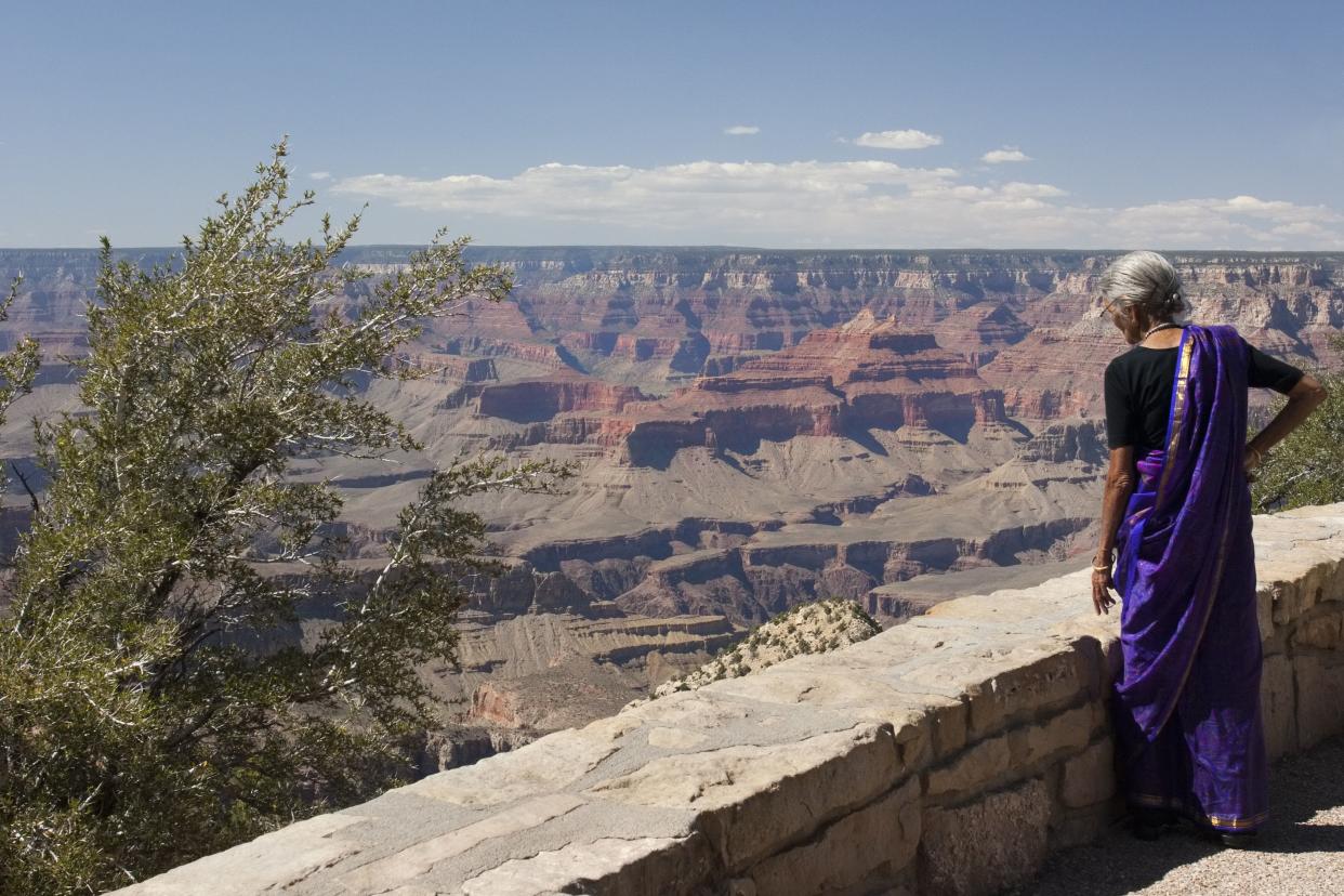 Arizona, United States of America - May 28, 2007: An elderly woman from East Asian wearing a purple sari is admiring the Grand Canyon from one of  its many observation platforms.