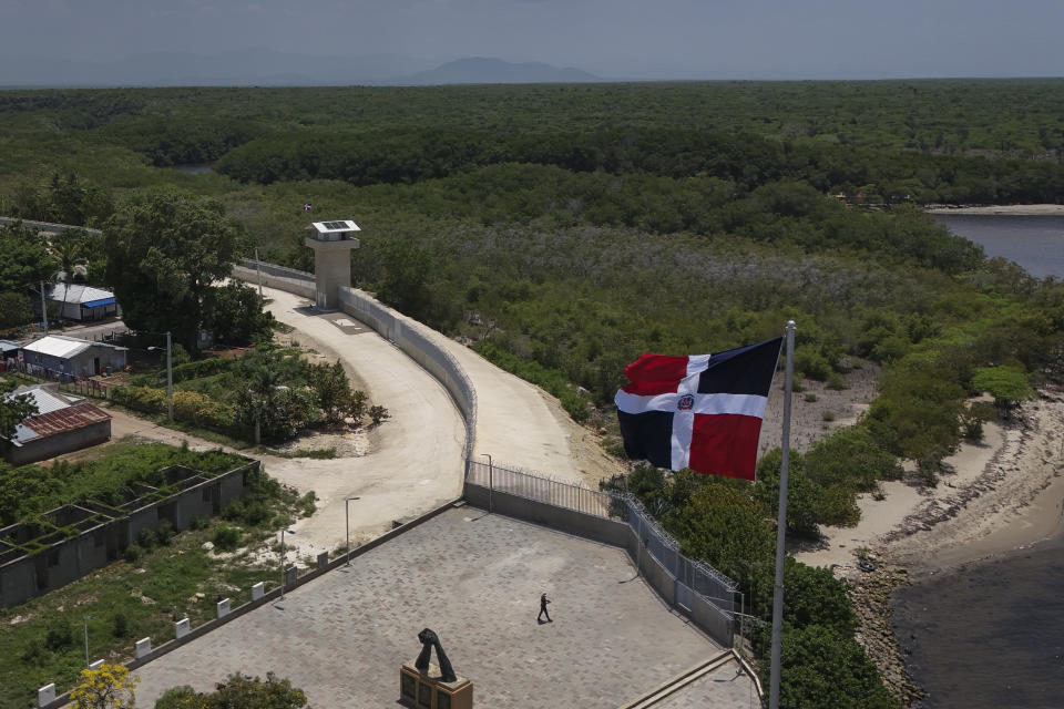 A national flag flies over a miles-long wall built by the Dominican Republic, that runs along the Haitian border, as seen from Pepillo Salcedo, Friday, May 17, 2024. As soaring violence and political turmoil grip neighboring Haiti, the Dominican Republic will hold elections Sunday that have been defined by calls for more crackdowns on migrants and finishing a border wall dividing the countries. (AP Photo/Matias Delacroix)