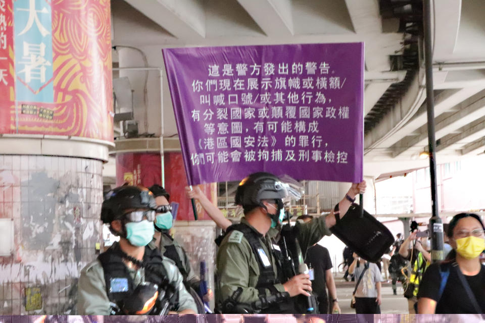 「港區國安法」生效，港警1日面對自行上街「七一」遊行的群眾，首度舉出了象徵執行此法的紫色旗幟。(中央社) 
