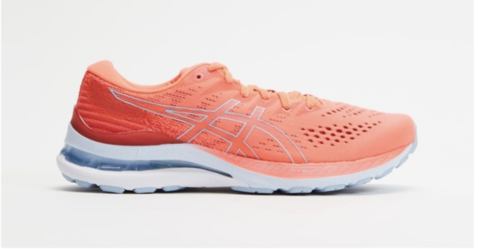 A pair of salmon/orange Asics trainers with blue-grey foam sole on a grey background