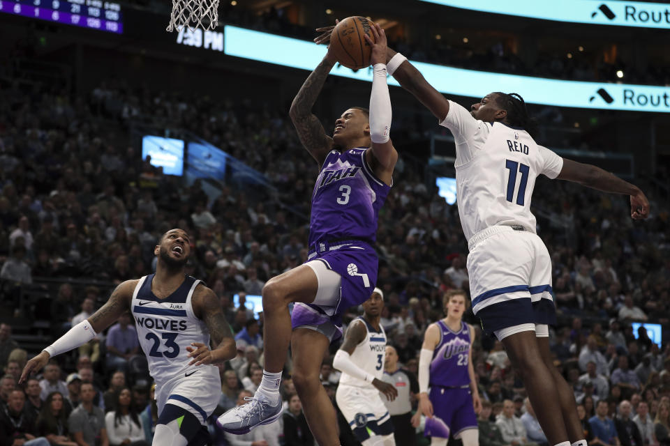 Utah Jazz guard Keyonte George (3) shoots past the outstretched arm of Minnesota Timberwolves center Naz Reid (11) while guard Monte Morris (23) watches during the first half of an NBA basketball game Monday, March 18, 2024, in Salt Lake City. (AP Photo/Adam Fondren)