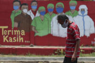 A man wearing a face mask walks past a coronavirus-themed mural in Jakarta, Indonesia, Thursday, Oct. 1, 2020. (AP Photo/Achmad Ibrahim)