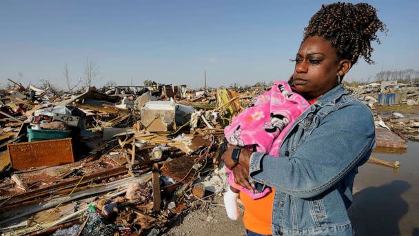 PHOTO: Wonder Bolden cradles her year-old granddaughter Journey Bolden as she surveys the remains of her mother's tornado demolished mobile home in Rolling Fork, Miss., Mar. 25, 2023. (Rogelio V. Solis/AP)