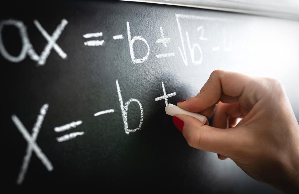 Math equation, function or calculation on chalkboard. Teacher writing on blackboard during lesson and lecture in school classroom. Student or tutor calculating or professor working.