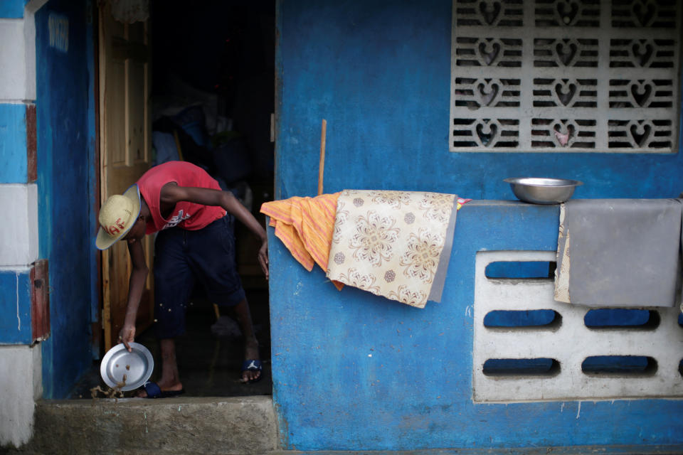 A man uses a metal plate to remove water from his house in Fort Liberte, Haiti
