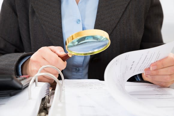 Looking at a book using a magnifying glass.