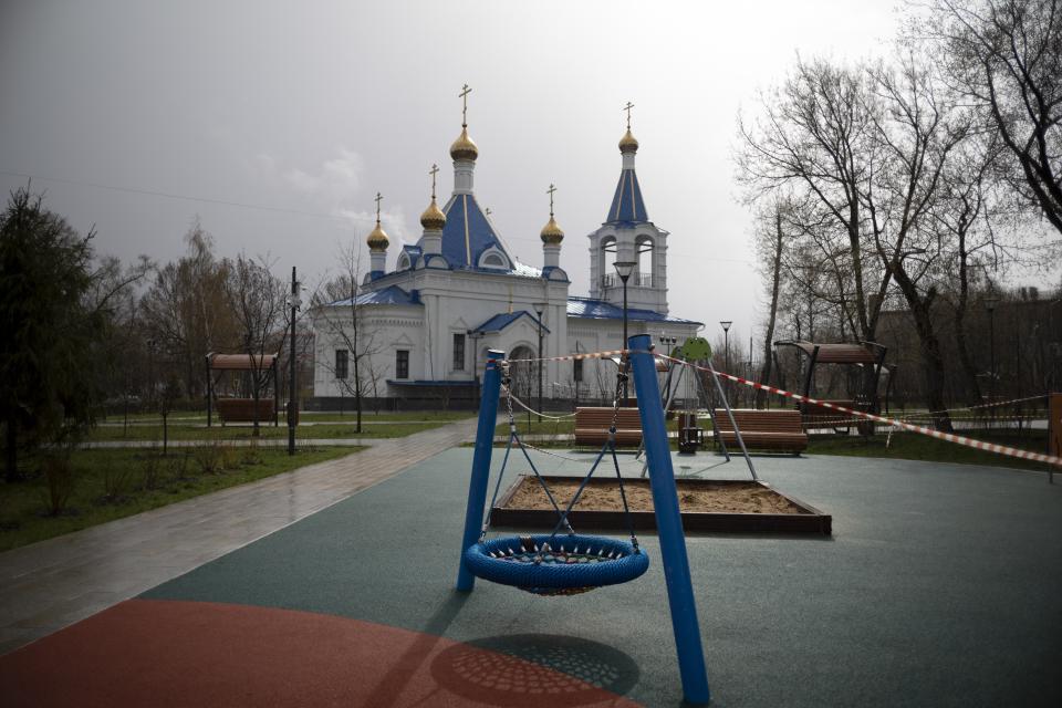 A caution tape cordons off an empty children's playground with an Orthodox church seen in the background, officially closed for parishioners according to the order of the city authorities due to coronavirus, in an almost empty square in Moscow, Russia, Saturday, April 18, 2020. For Orthodox Christians, this is normally a time of reflection, communal mourning and joyful release, of centuries-old ceremonies steeped in symbolism and tradition. But this year, Easter - by far the most significant religious holiday for the world's roughly 300 million Orthodox - has essentially been cancelled. (AP Photo/Alexander Zemlianichenko)