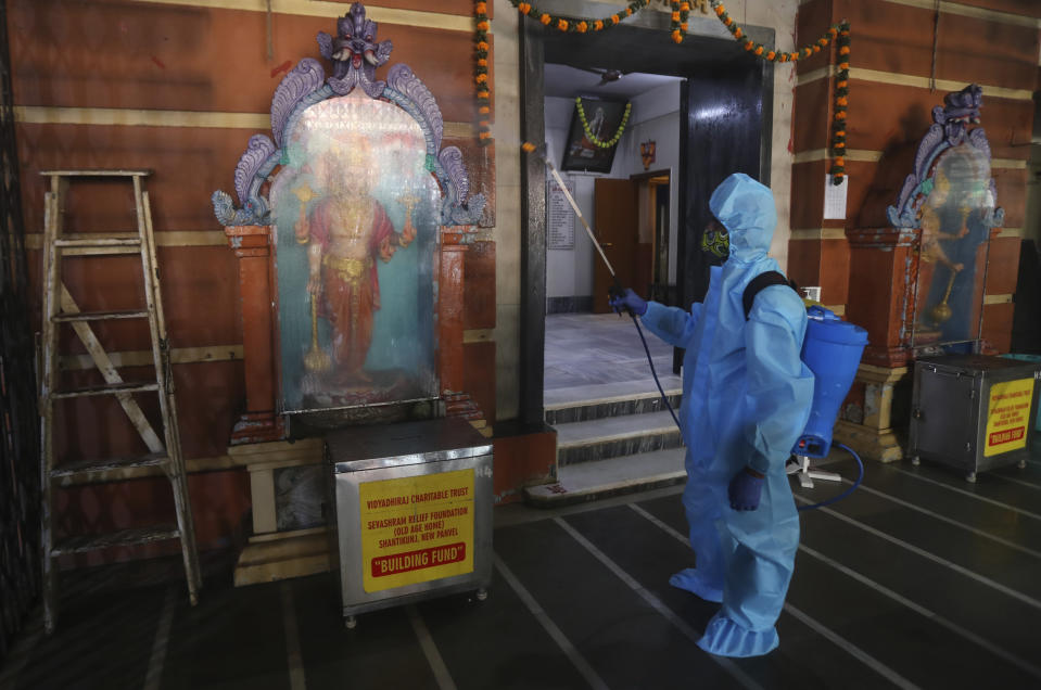 An employee sanitizes a Hindu temple in Mumbai, India, Sunday, Nov. 15, 2020. India is second in the world in total reported coronavirus cases behind the U.S., but daily infections have been on the decline since the middle of September. (AP Photo/Rafiq Maqbool)