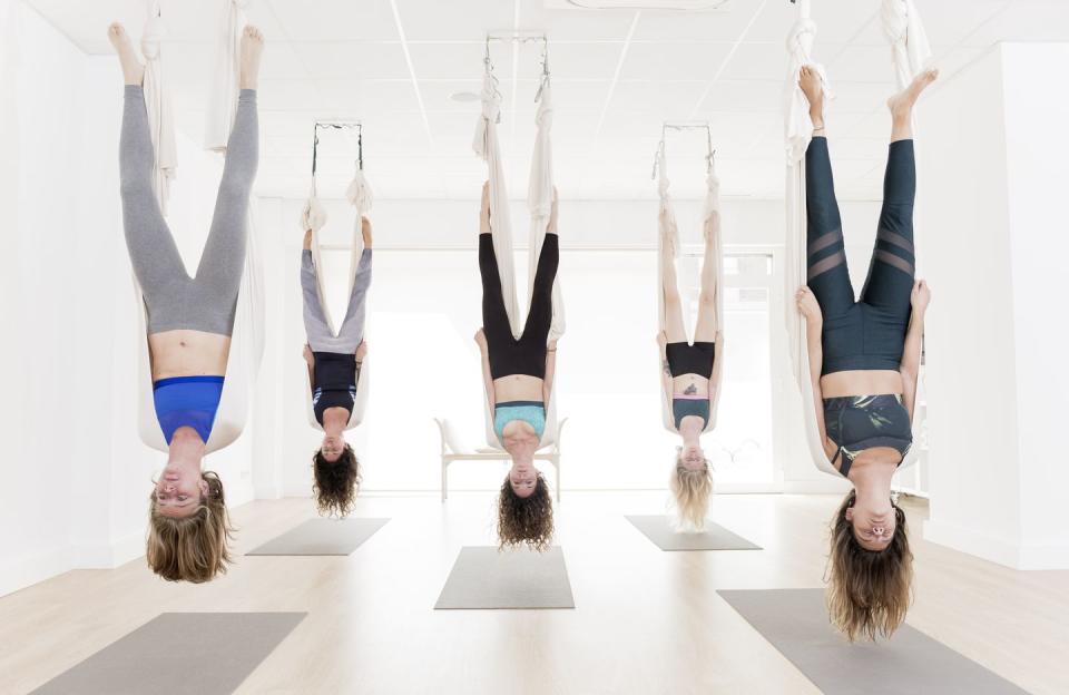 women exercising upside down during aerial yoga class