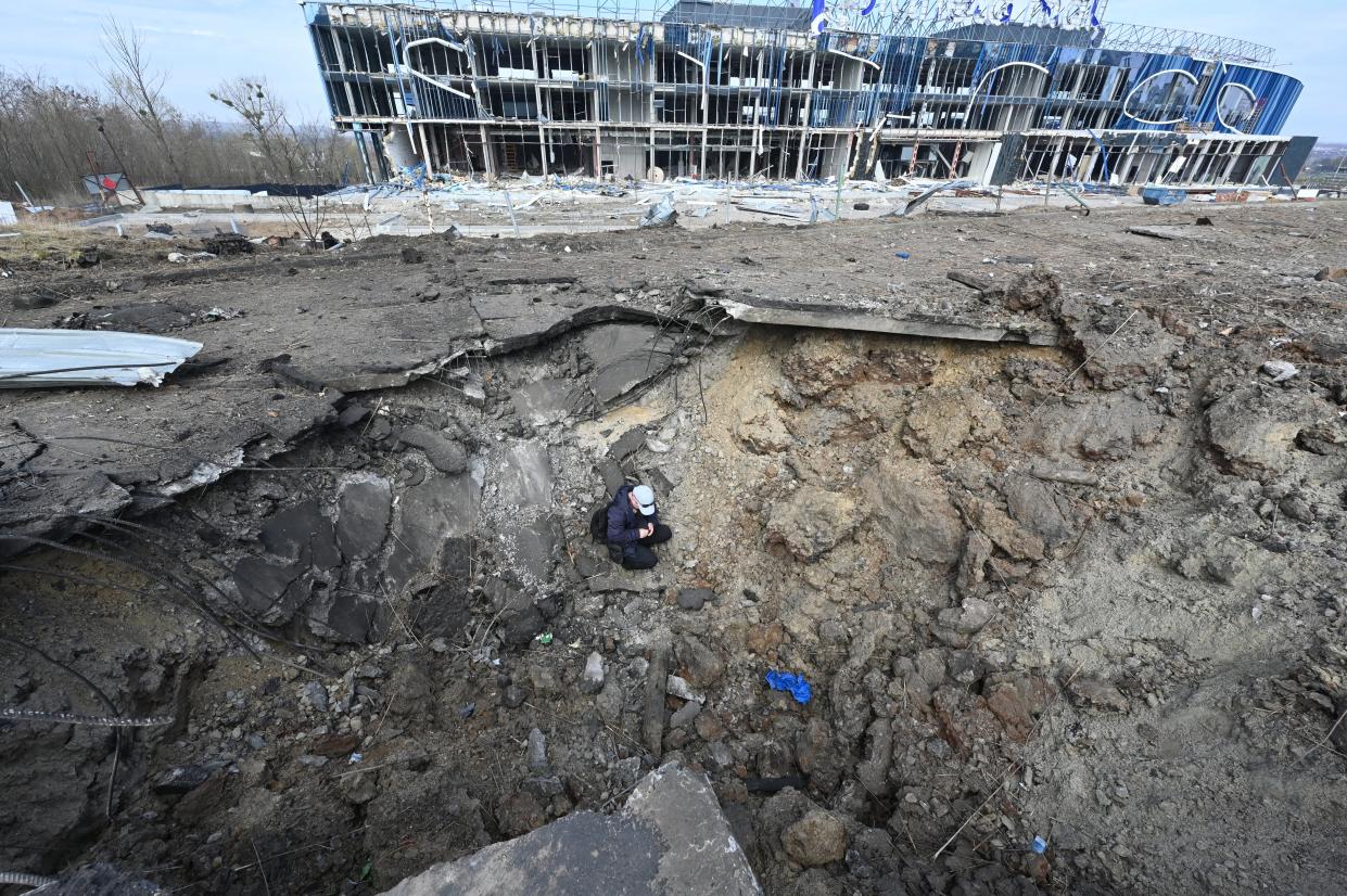 A communal worker sits in a crater after missiles strike in Kharkiv (AFP via Getty Images)