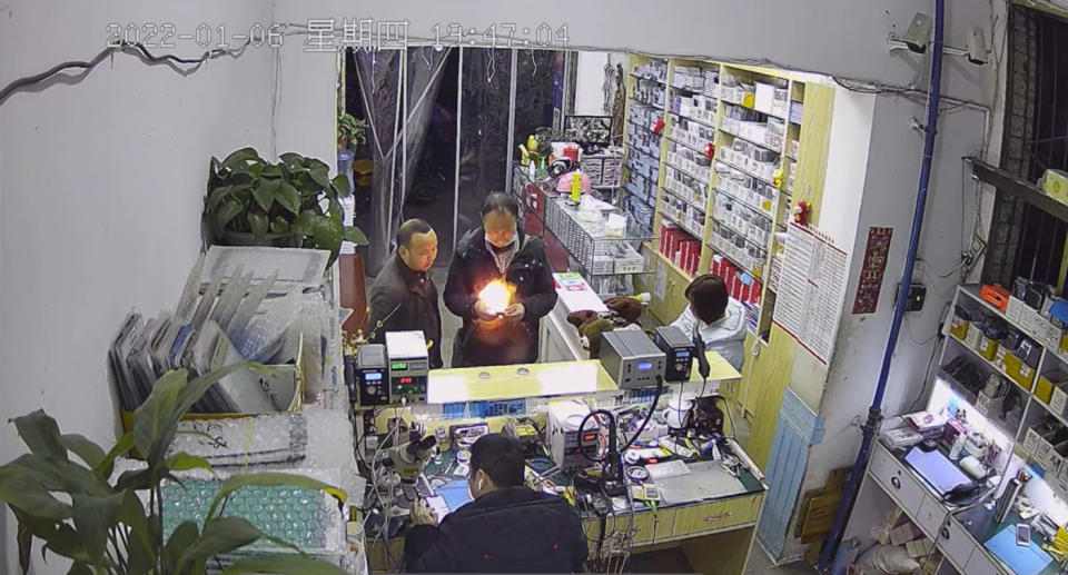 A mobile phone explodes into flames while in a man&#39;s hands in a repair shop in China.