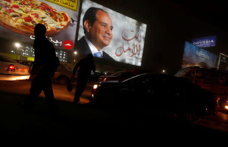 People walk near a billboard showing a picture of Egyptian President Abdel Fattah al-Sisi during the presidential election in Cairo, Egypt, March 28, 2018. REUTERS/Amr Abdallah Dalsh