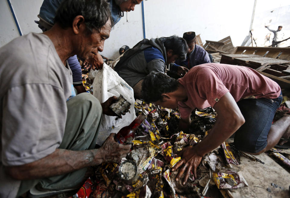 In this Wednesday, Oct. 3, 2018, photo, men dig through sodden piles of food inside an abandoned warehouse following an earthquake and tsunami in Palu, Central Sulawesi, Indonesia. (AP Photo/Dita Alangkara)